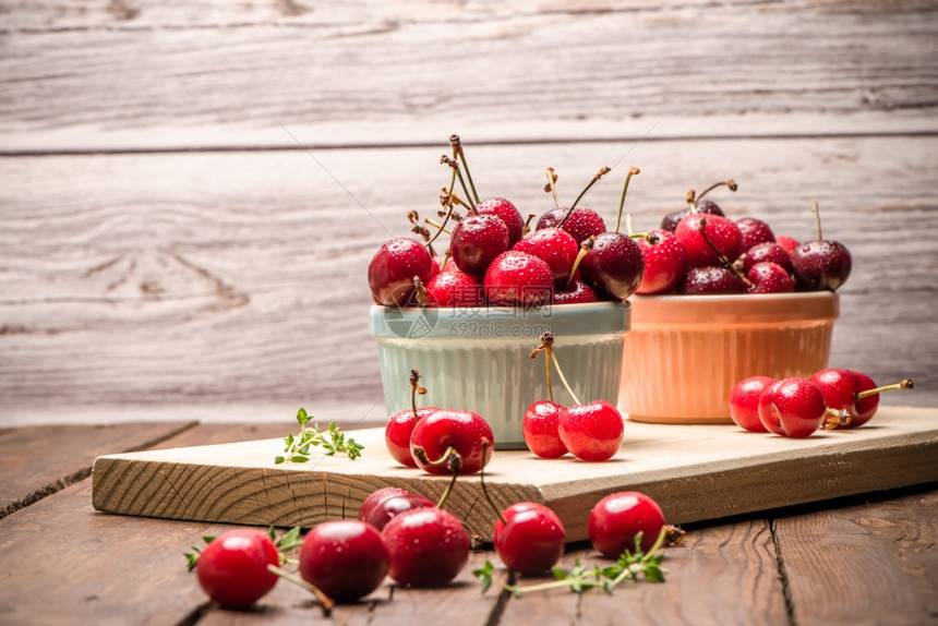 在木制厨房柜台的陶瓷碗里红色的成熟樱桃图片