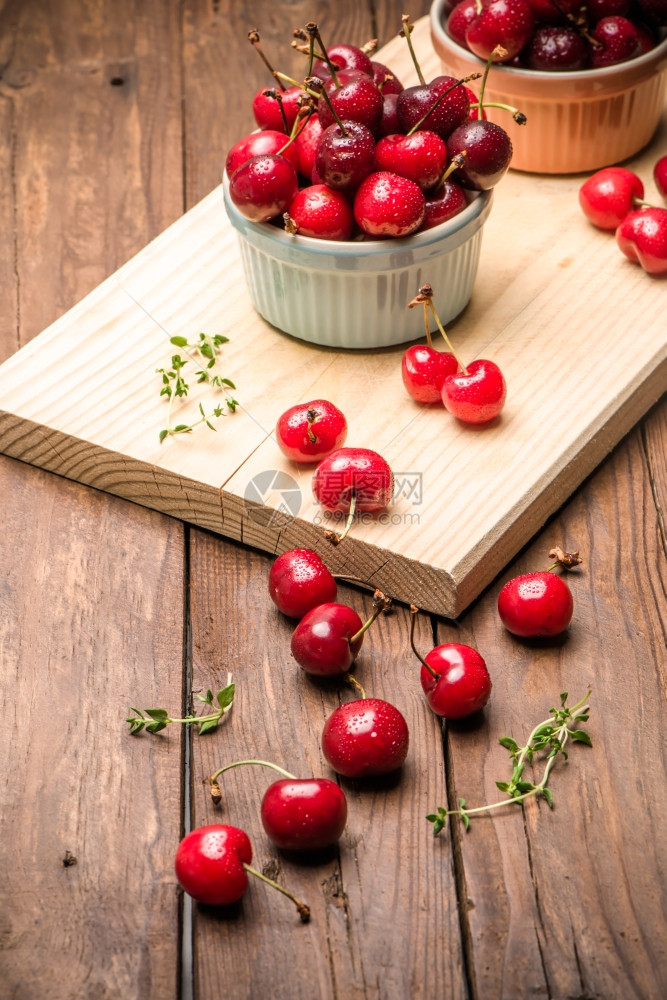 在木制厨房柜台的陶瓷碗里红色的成熟樱桃图片