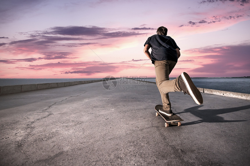 在日落时滑板机沿港口推着水泥路行驶图片