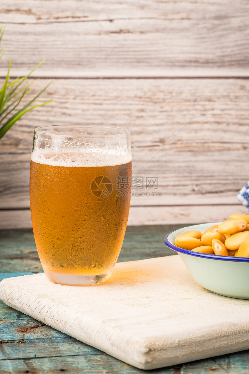 金属杯子里的酸润滑油木制桌子顶上的啤酒杯图片