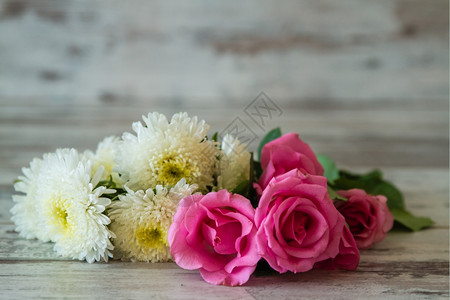 白木背景的粉红玫瑰和白花背景