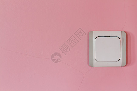 粉红色墙上的旧白灰电开关背景图片