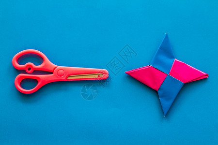 粉红色玩具剪刀和蓝纸背景上的折星图片