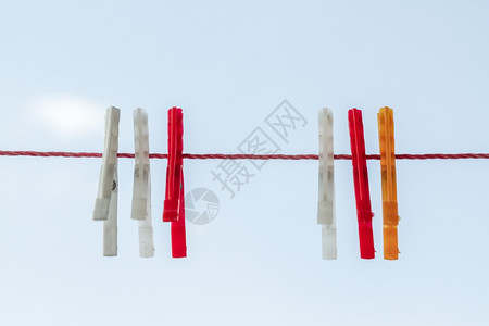 白色红橙布针挂在蓝天空的红绳上图片