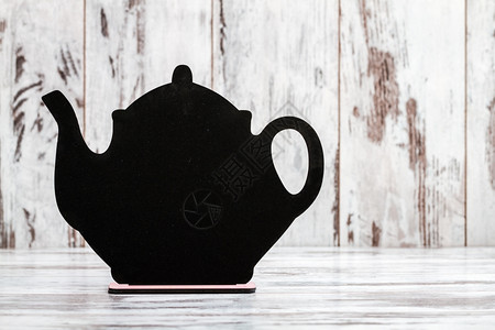 用茶壶形状在白木背景上写作的装饰黑白板图片