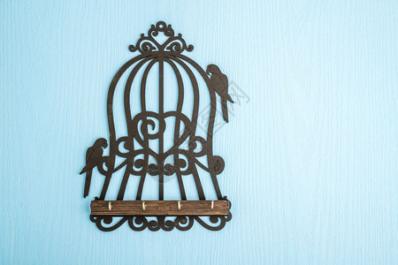 蓝木背景的鸟笼形状木制钥匙机架图片