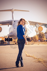 女孩站在旧飞机旁摆姿势背景图片