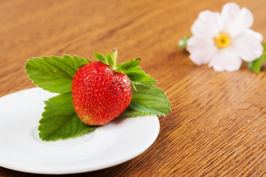 美丽的多汁草莓灰地和盘子上本底有花朵图片