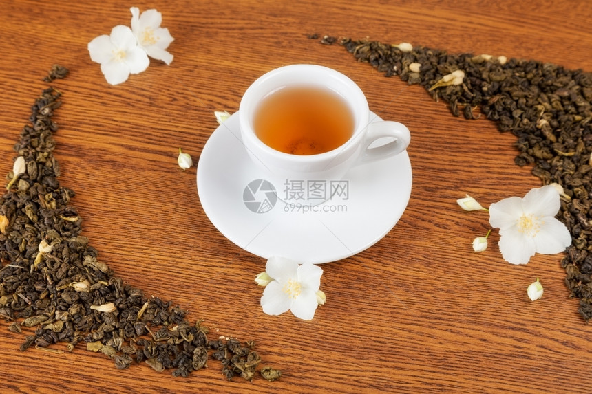 白色杯子和茶碟木制桌上有茉莉花背景图片