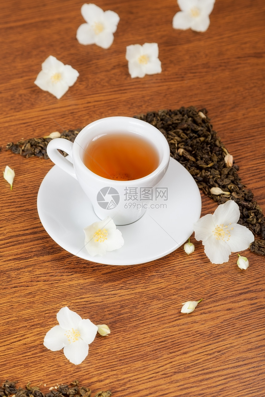 白色杯子和茶碟木制桌上有茉莉花背景图片