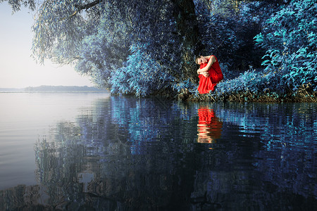 穿着红裙子的迷人女孩坐在河岸上美丽时尚户外艺术风格图片