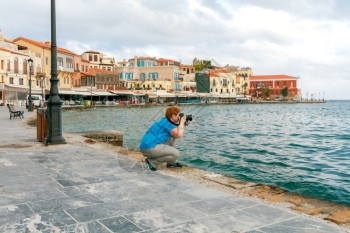 在Chania水边的Chania水边的女子拍摄了老威尼斯港的照片图片
