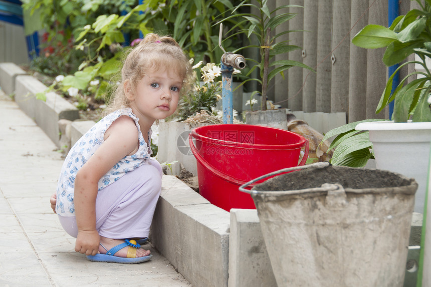 女孩站在起重机浇水的院子里图片