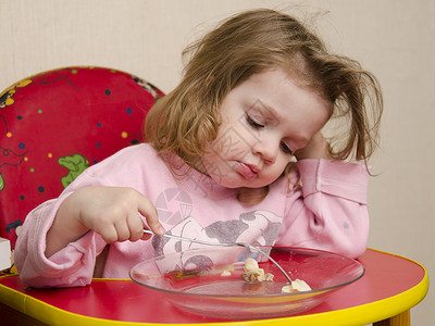 两岁女孩坐在厨房的桌子上吃东西女孩用叉子吃饭图片