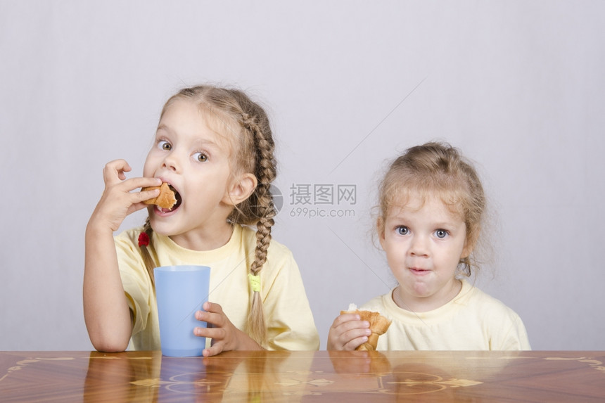 两个孩子坐在桌上吃早餐图片