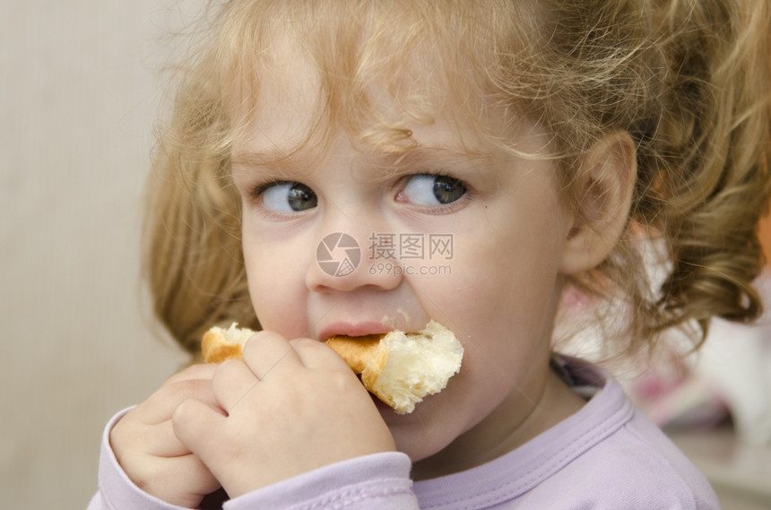 小女孩坐在桌子上热情地吃着卷子图片