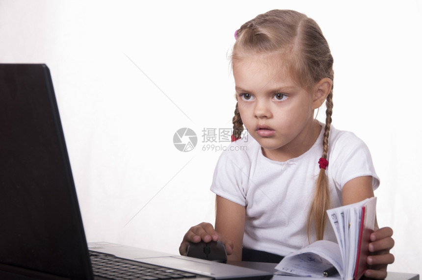 女孩坐在桌子上是笔记本电脑女孩工作愉快地看另一只笔记本电脑打开笔记本电脑图片