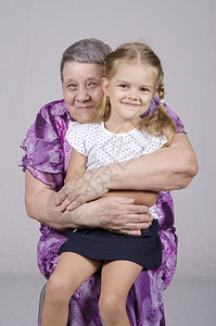 一个80岁的老年妇女肖像在一个女人的膝上坐在孙女的膝盖上坐了四年背景图片