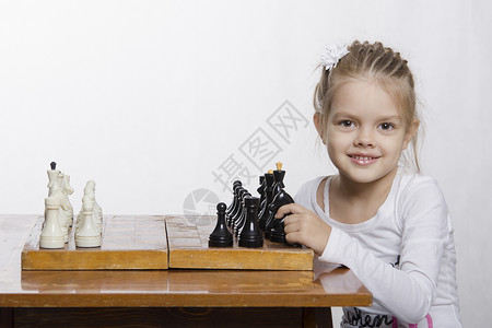 坐在桌子上的女孩站在棋局上女孩正在学习如何下棋图片