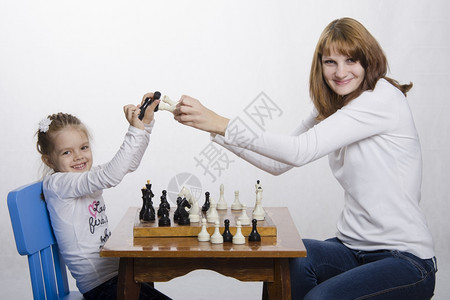 母亲和女儿在象棋桌边玩母亲教女儿游戏他们一起打几个碎片很有趣图片