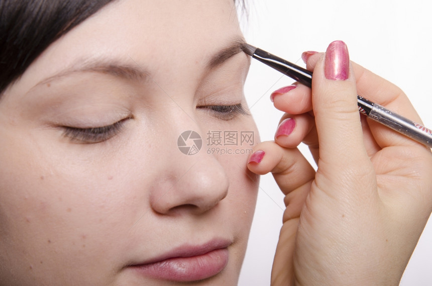 化妆师在模特的脸上做化妆品她领导眉笔模型图片