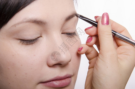 化妆师在模特的脸上做化妆品她领导眉笔模型背景图片