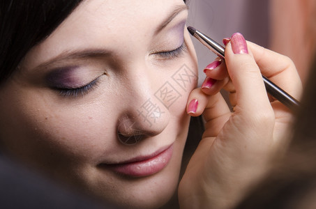化妆师在模型Q39上做化妆品脸她画上层眼皮模型的阴影背景图片