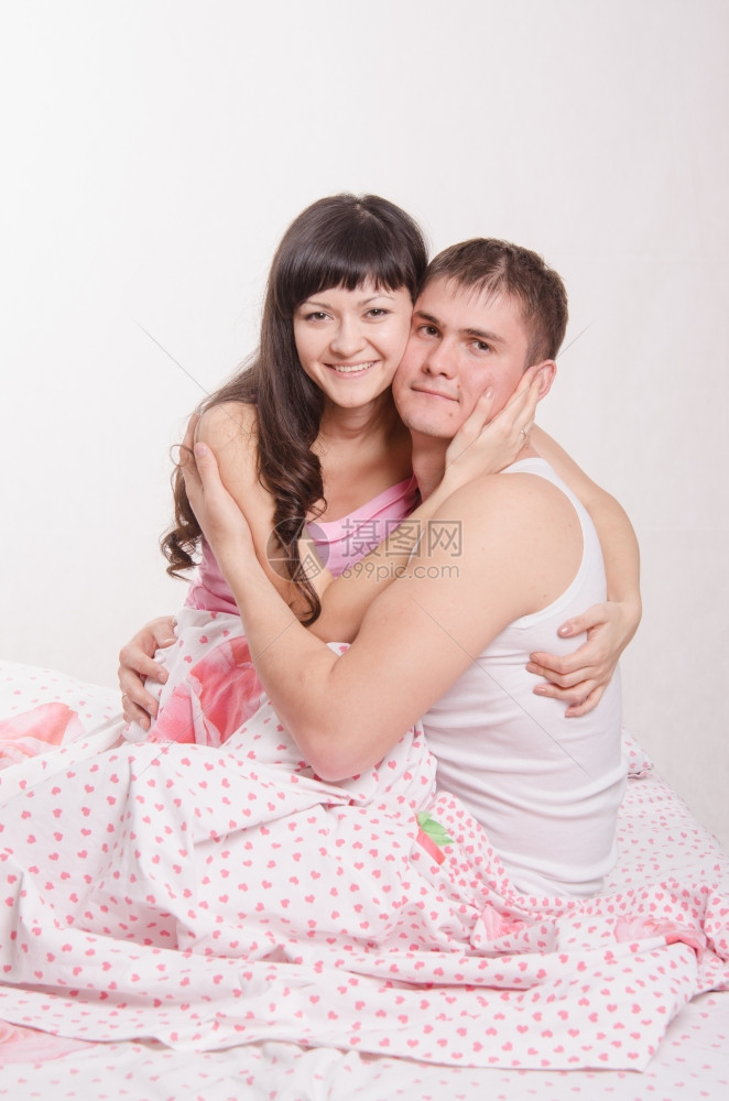 年轻一对坐在床上互相拥抱的年轻一对图片