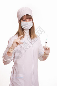 身穿白外套帽子手和面具拿着注射器和瓶子的医务工作者肖像图片