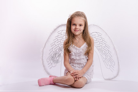 白色的天使6岁女孩穿着明亮的天使服装白色背景有翅膀白色背景的坐着女孩背景