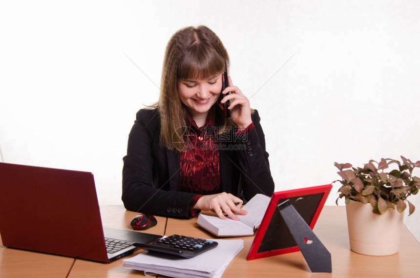 在计算机办公室的可爱女商人主管办公室后面的女孩通过电话进行对图片