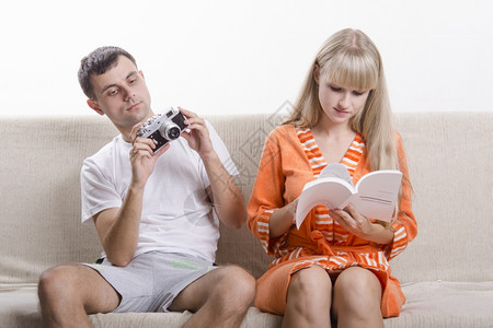 哈沙克一个男孩和一个女孩坐在沙发上那家伙转向你手中的相机那女孩读着说明书背景