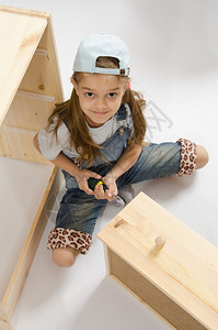 小女孩家具收藏在胸前木框中用螺丝刀扭起子图片