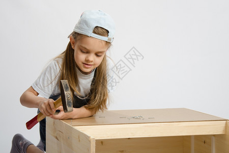 6岁女孩玩耍和收集木制柜子课堂上的女孩努力用锤子钉图片