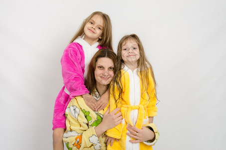 有两个女儿坐在白色背景的浴袍上身穿的母亲和两个女儿身着浴袍图片