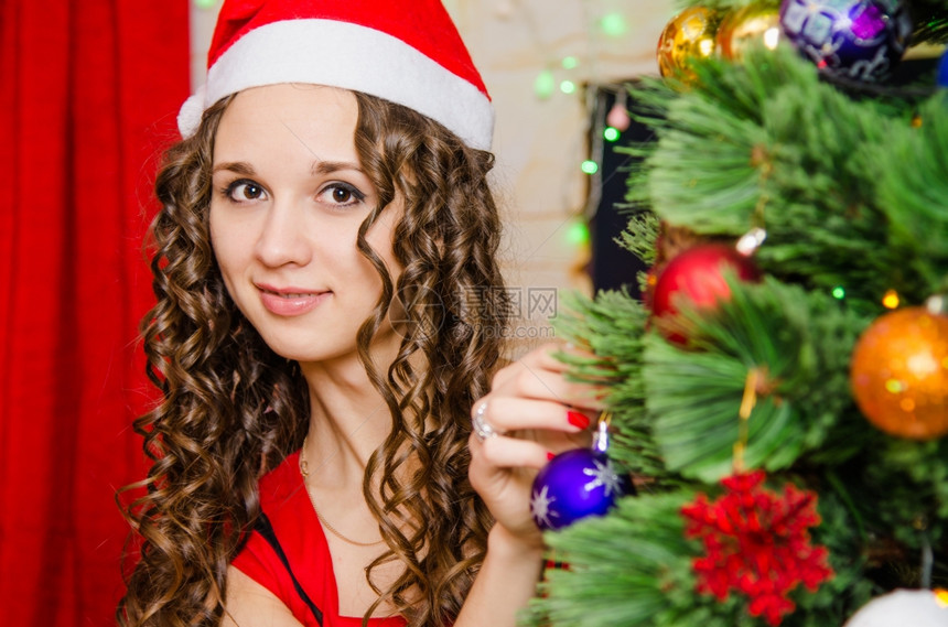 年轻美丽的女孩装饰圣诞树玩具年轻女孩打扮成圣诞树图片