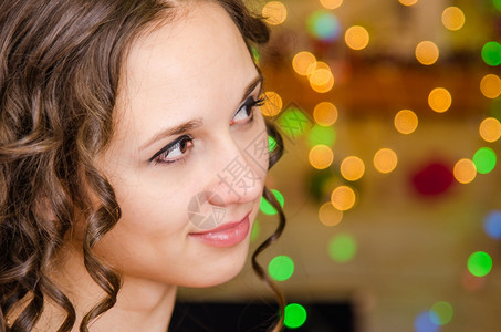 在圣诞灯光模糊的背景下一个年轻的欧洲女孩近距离肖像背景图片