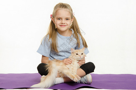 健身的猫素材坐在地毯上抚摸猫腿的快乐女孩与家猫一起坐在地毯上运动后六岁的欧洲女孩与家猫一起在地毯上运动了六岁欧洲女孩背景