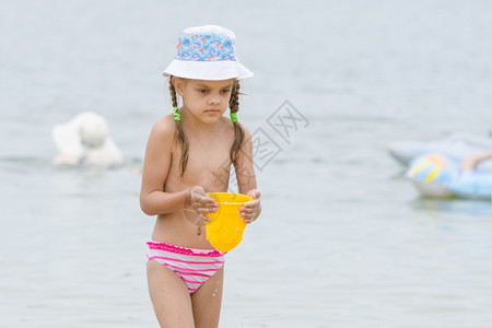 娃哈哈桶装水5岁女孩在海滩上用桶装水有趣的5岁女孩在海滩上玩沙模背景