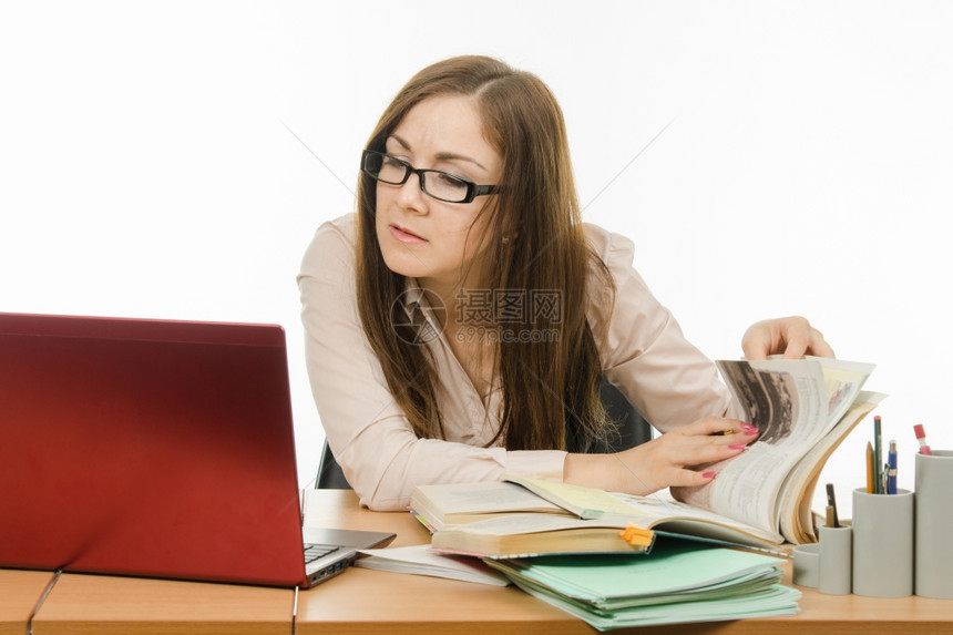 可爱的小女孩是一个教师坐在桌子上手持笔记本书和图片
