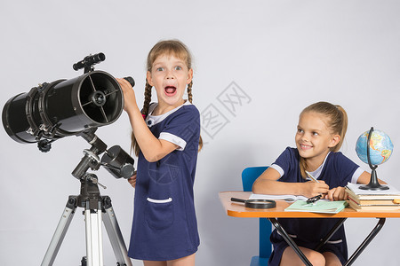 望远镜女孩女孩惊讶的天文学家通过望远镜观察另一女孩看着她背景