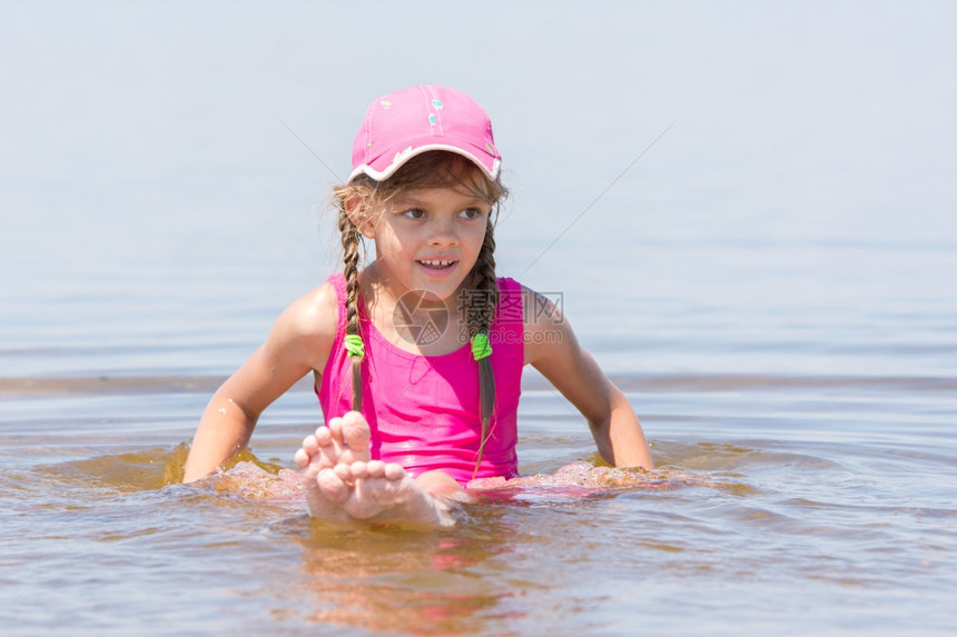 身着帽子的女孩坐在水中浅河边图片