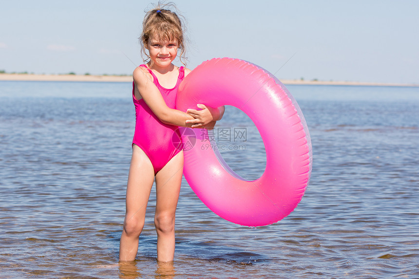 身穿粉红色泳衣的5岁女孩站在河里游泳圈图片