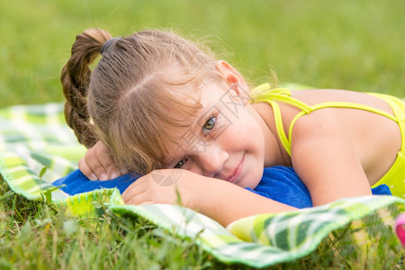 5岁女孩躺在绿色草地上触摸着框架图片