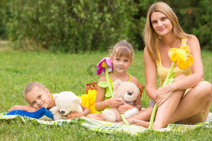 母女坐在野餐毯子上带着玩具图片