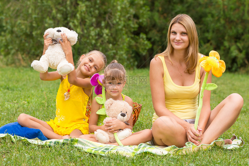 母亲和女儿与柔软玩具一起坐在野餐上图片
