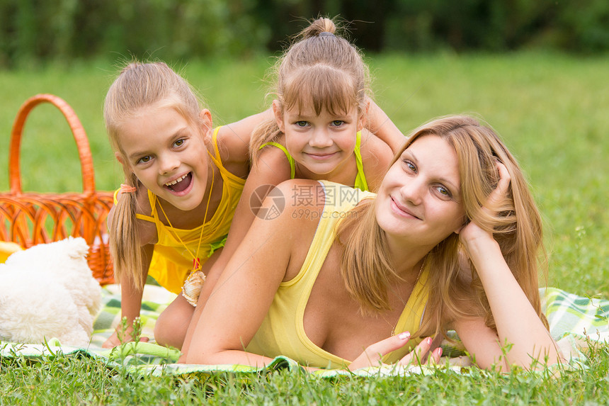 母亲和两个女儿在绿草上互相依恋图片