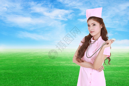 具有绿草地和天空背景听诊器的女护士图片