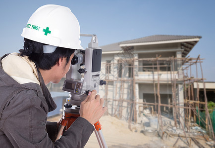 工程师使用时速计或具有房屋建筑工地背景的热土石图片