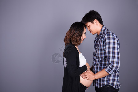 年轻夫妇母亲怀孕父快乐身穿灰墙图片